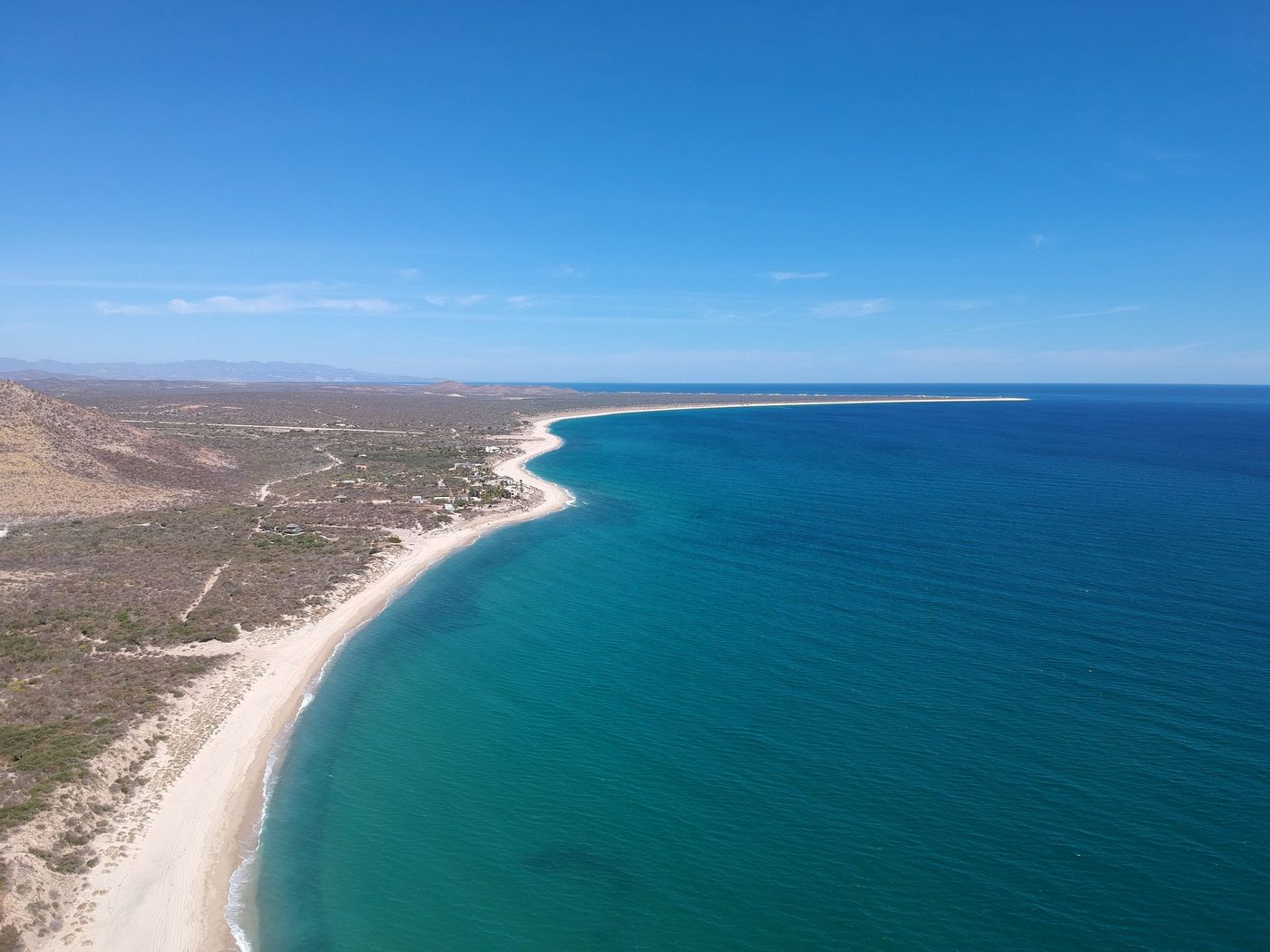 Aerial view of a long empty beach curving along the Baja desert
