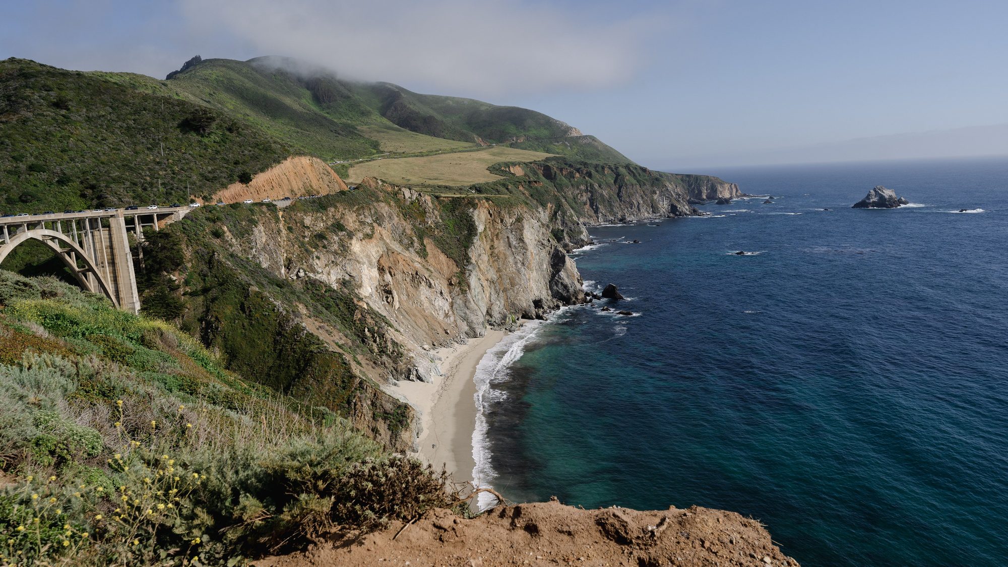 The Big Sur coast: green hills, cliffs and a bridge over a canyon above the Pacific