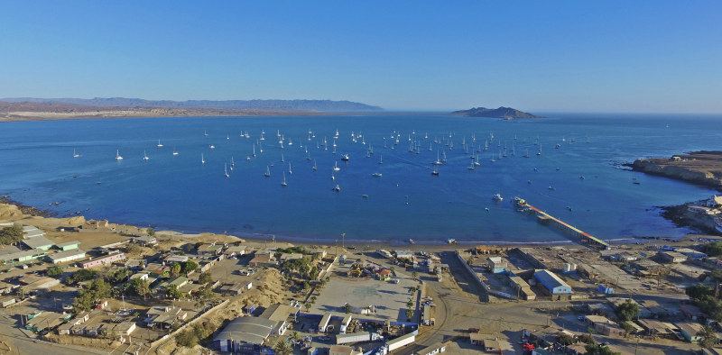 Aerial view of Bahía Tortugas: the town, the long fuel pier, and the Ha-Ha fleet anchored in the bay
